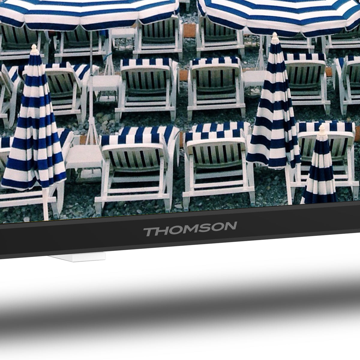 Outdoor setting with white chairs and blue striped umbrellas, featuring a Thomson monitor.