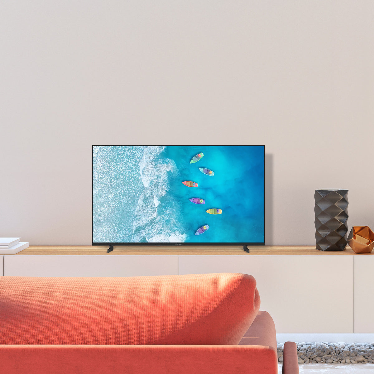 Smart TV displaying a beach scene with boats on a white wall in a living room.
