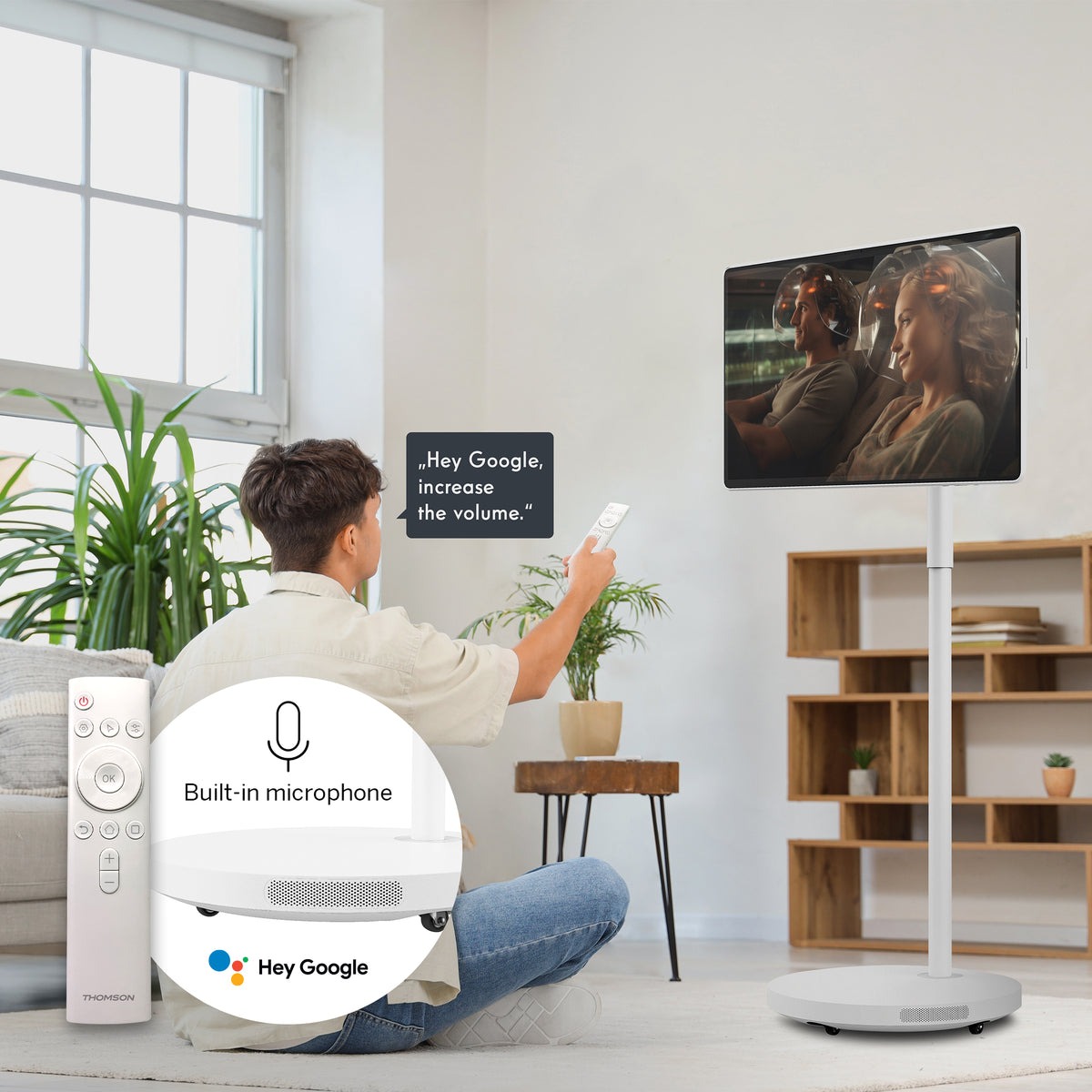 Person sitting on the floor with remote in hand pointing toward a mobilescreen, using voice control.